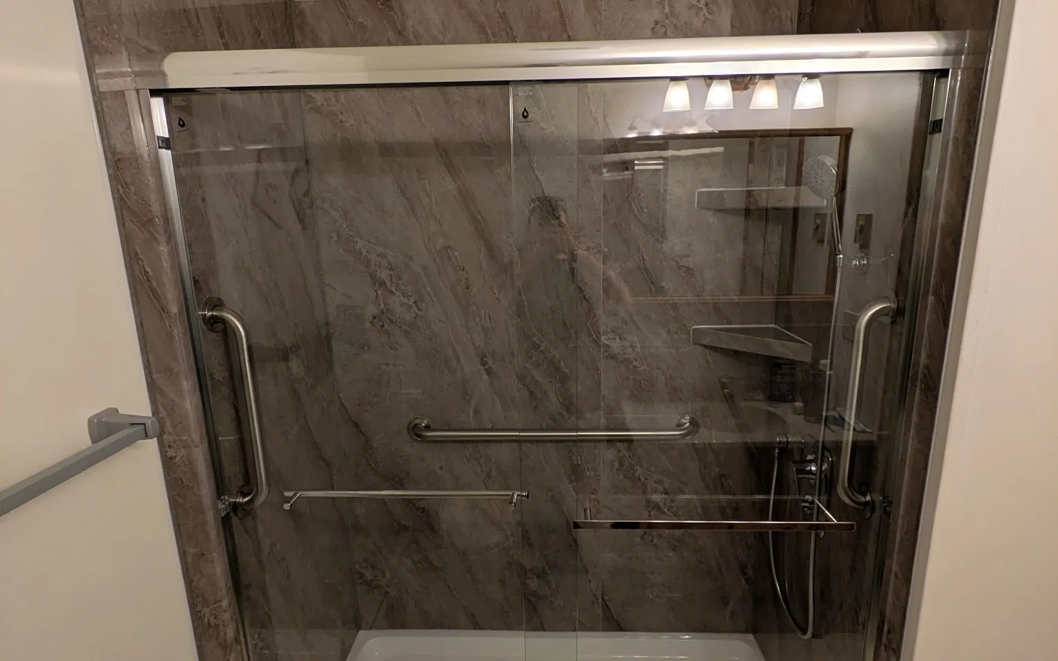 Stone-look shower enclosure with twin sliding glass doors and a low-threshold base