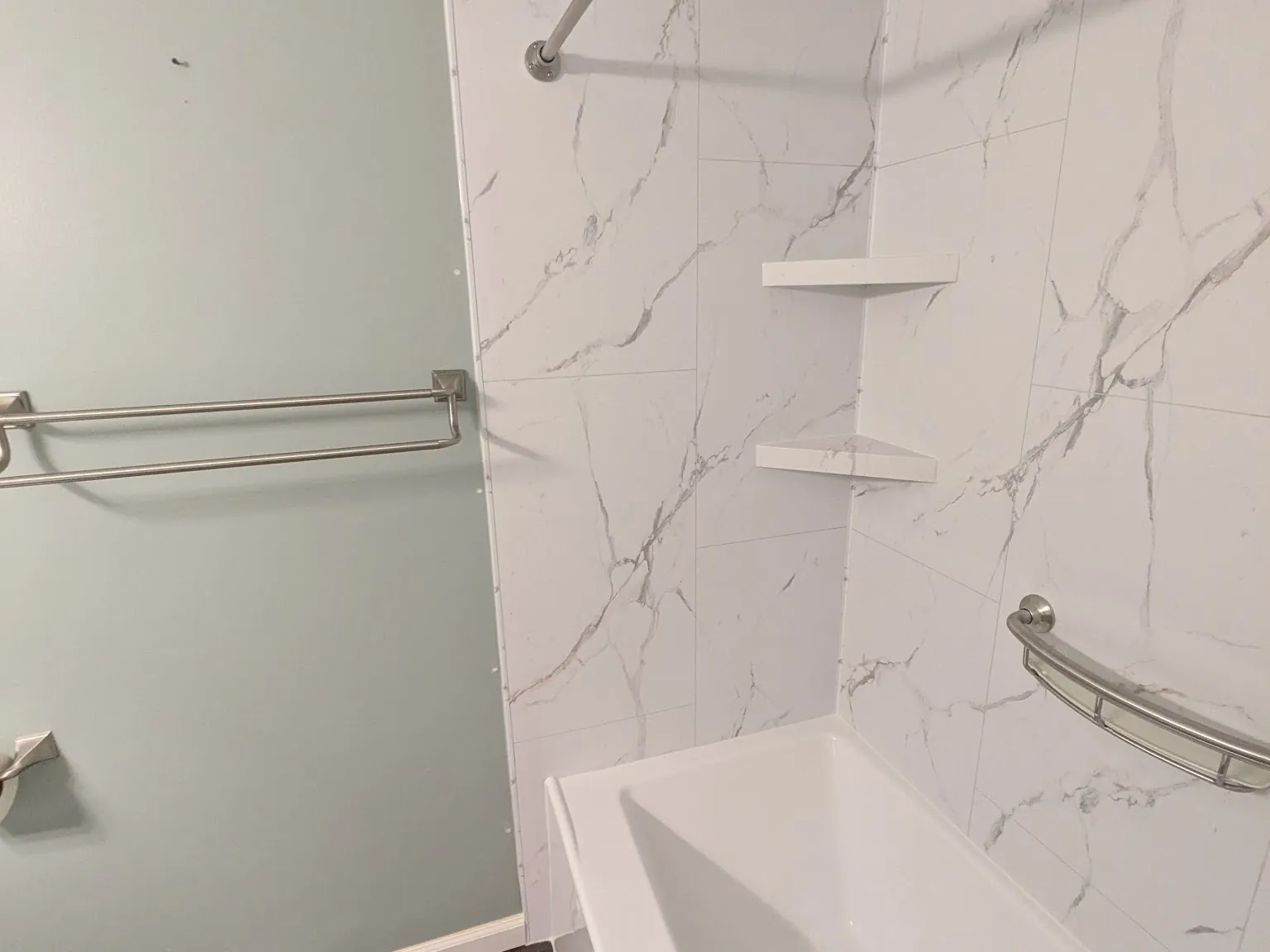 New soaking tub set into a white marble-look surround with brushed nickel fittings