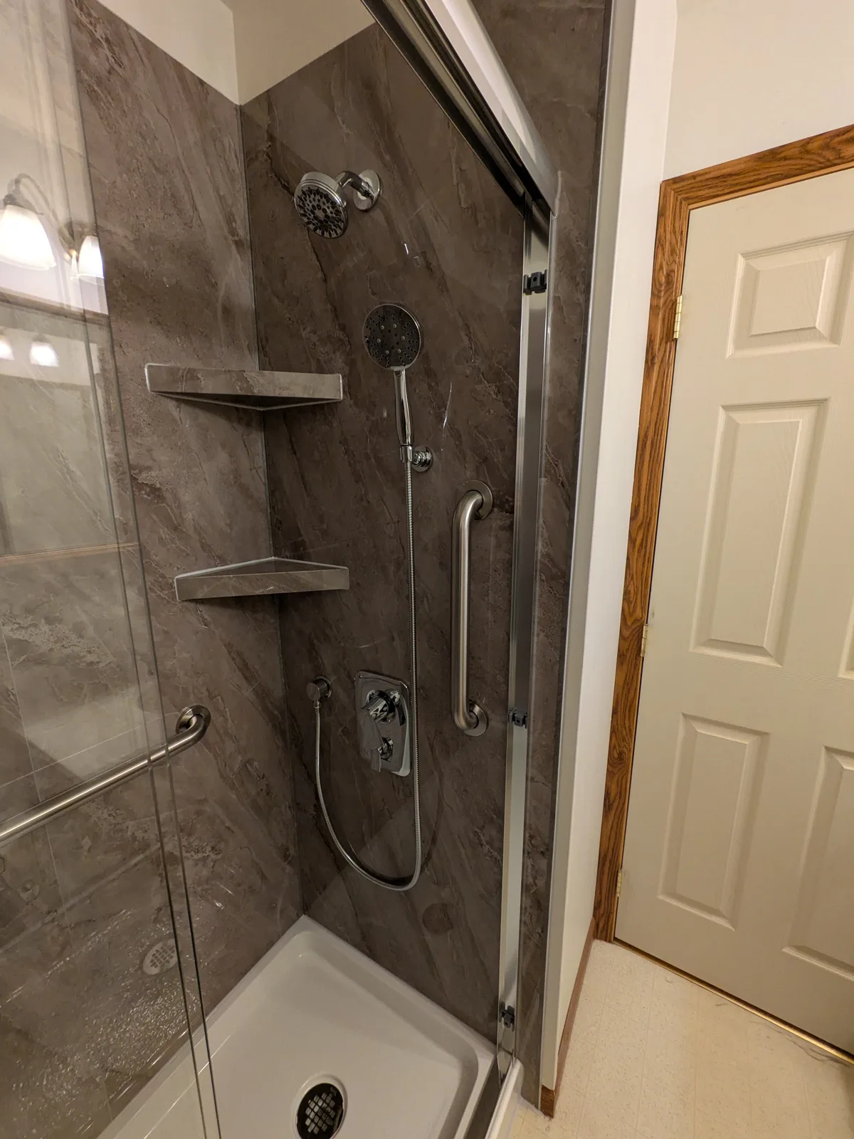 Finished walk-in shower with sliding glass and marble-look walls