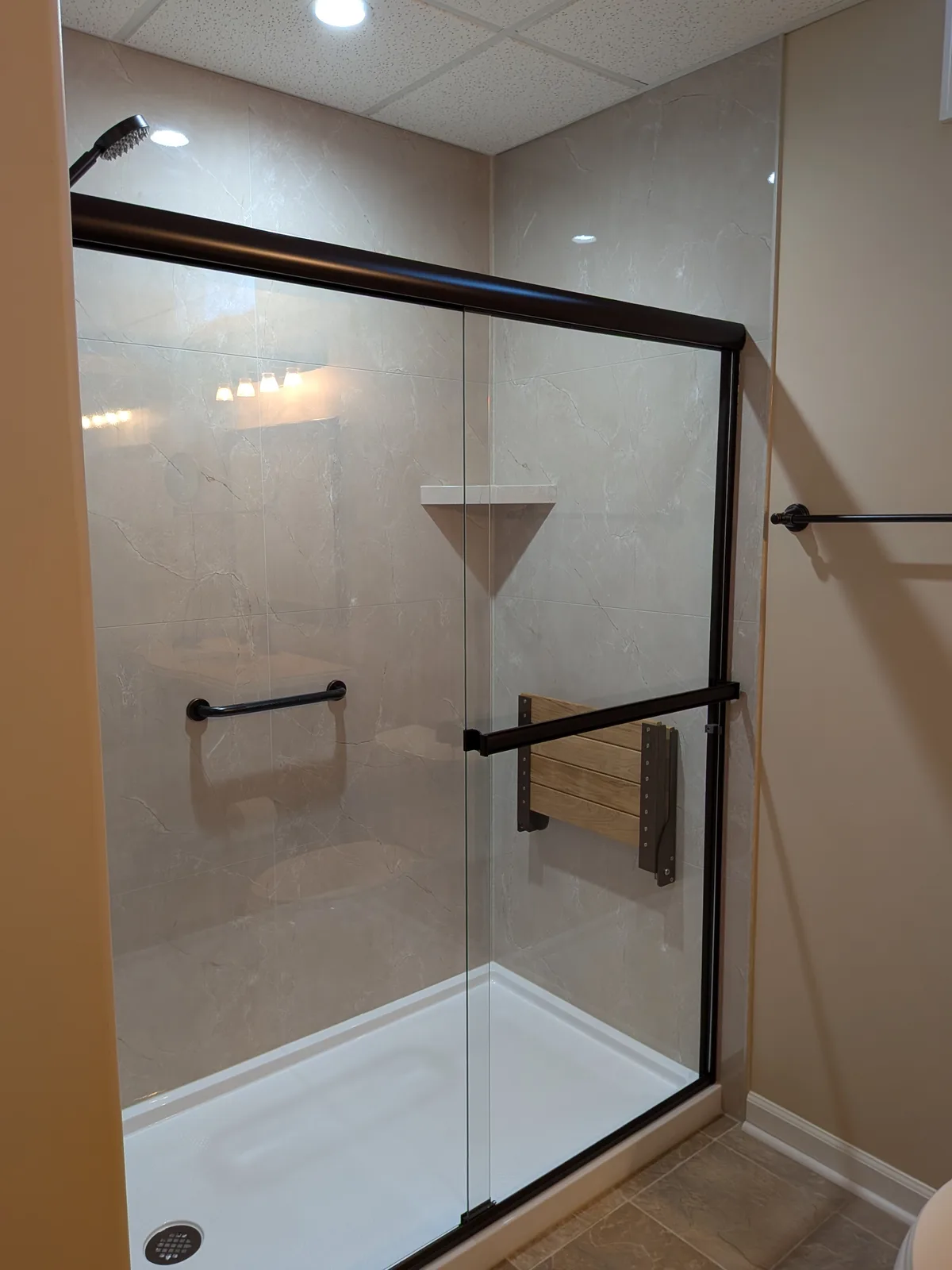 Walk-in shower from the side, showing the fold-down teak seat and sliding glass