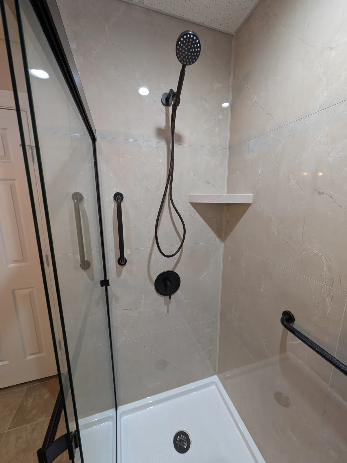 Finished shower alcove with black fixtures and a low-threshold base