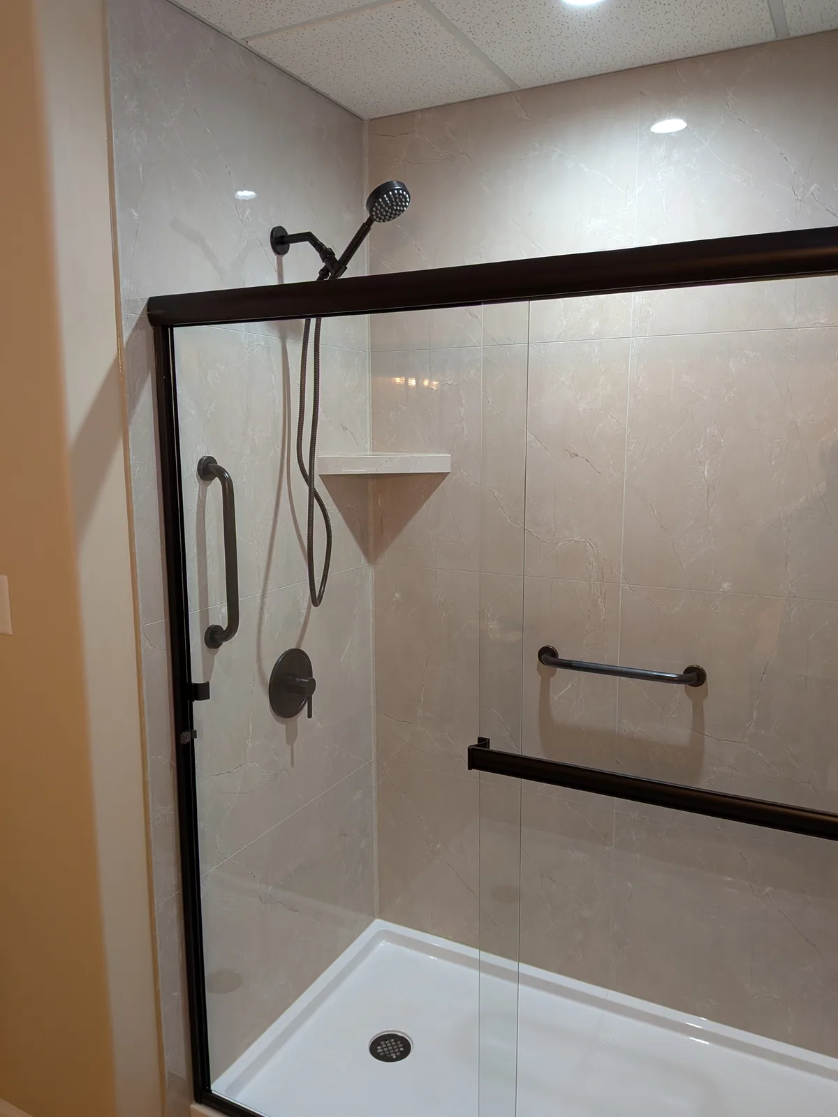Close view of the completed walk-in shower and bronze hardware