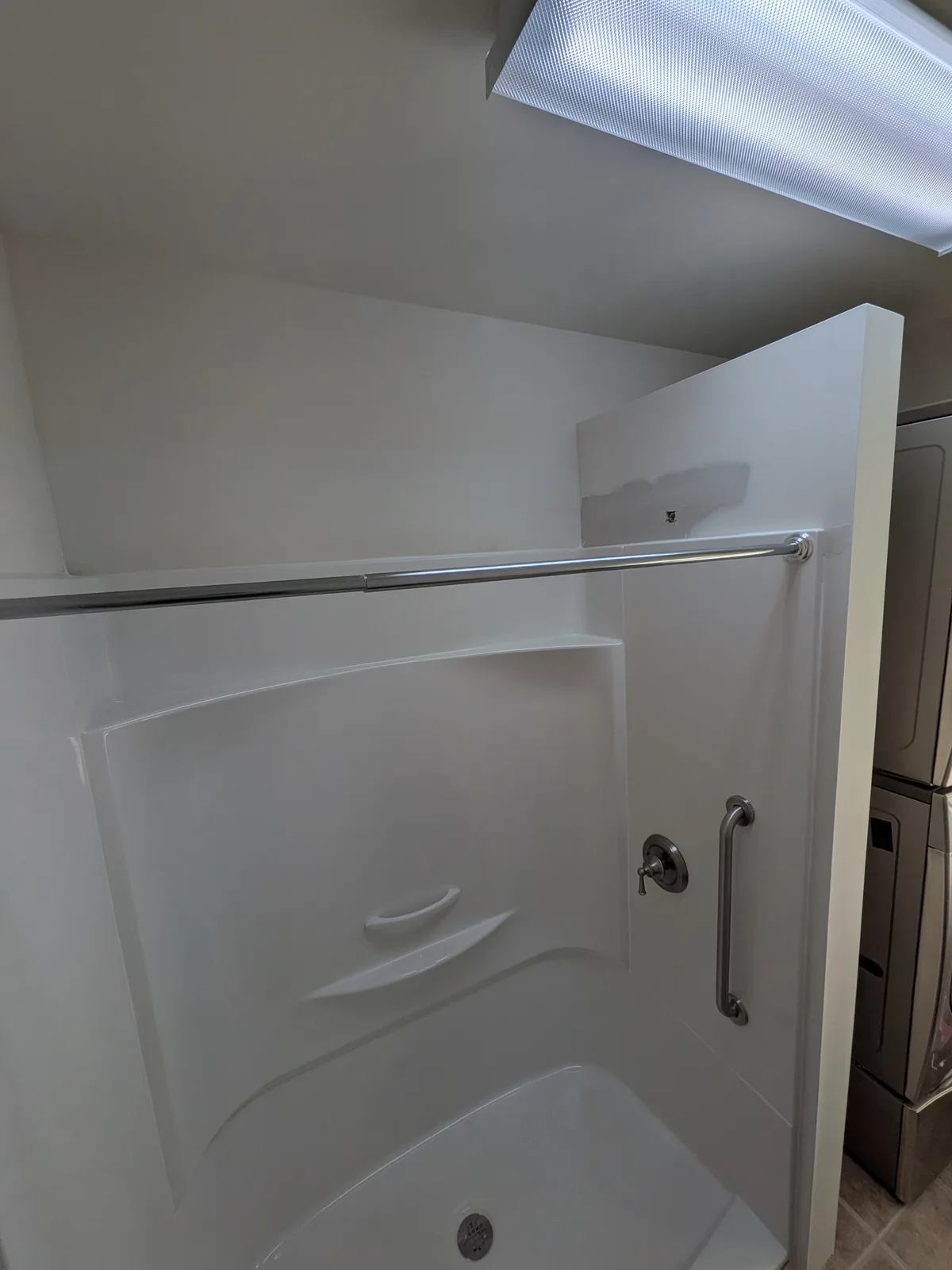 One-piece tub surround with grab bar and shower valve