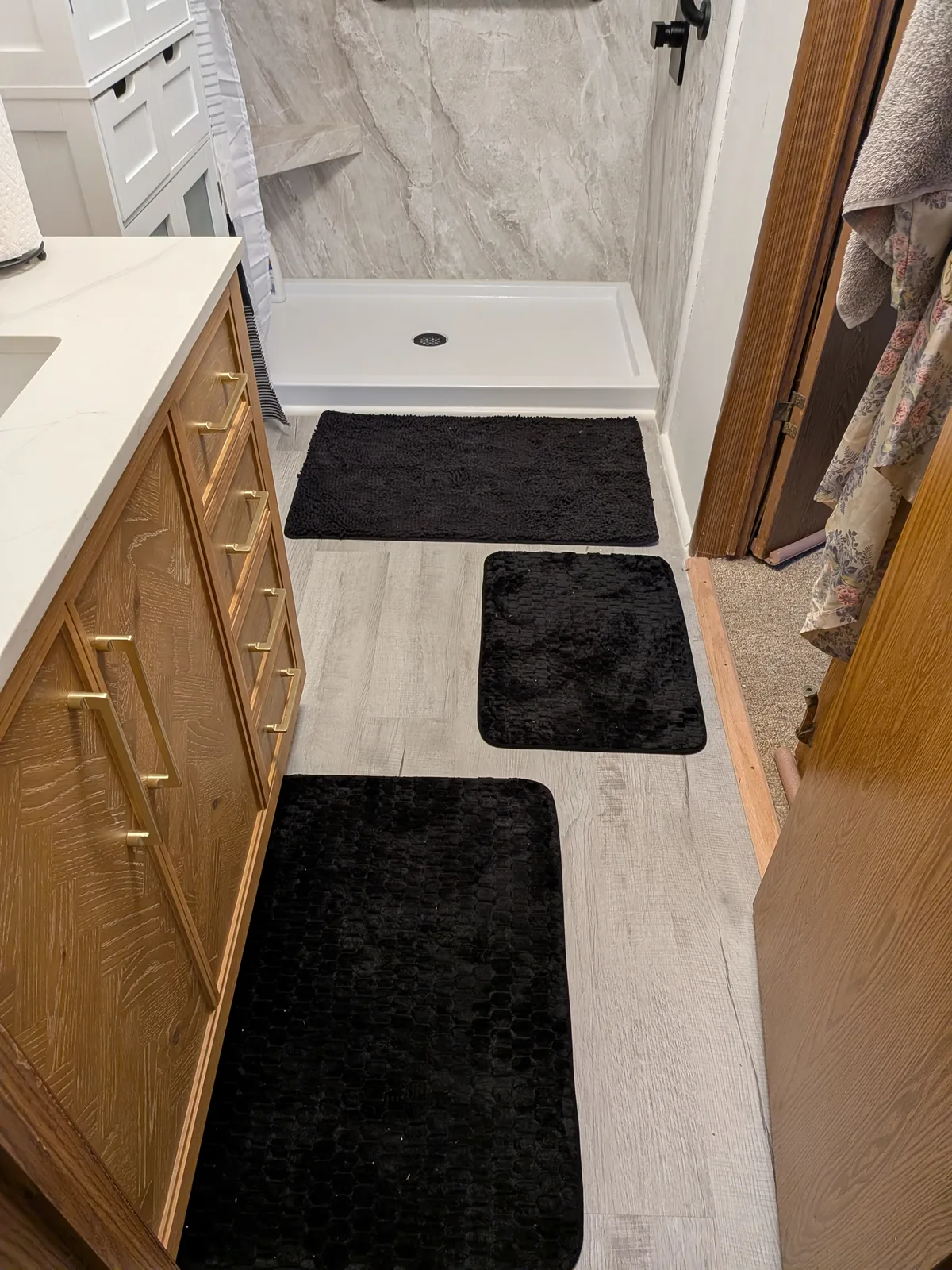 Walk-in shower with a built-in niche, black grab bars and a handheld shower