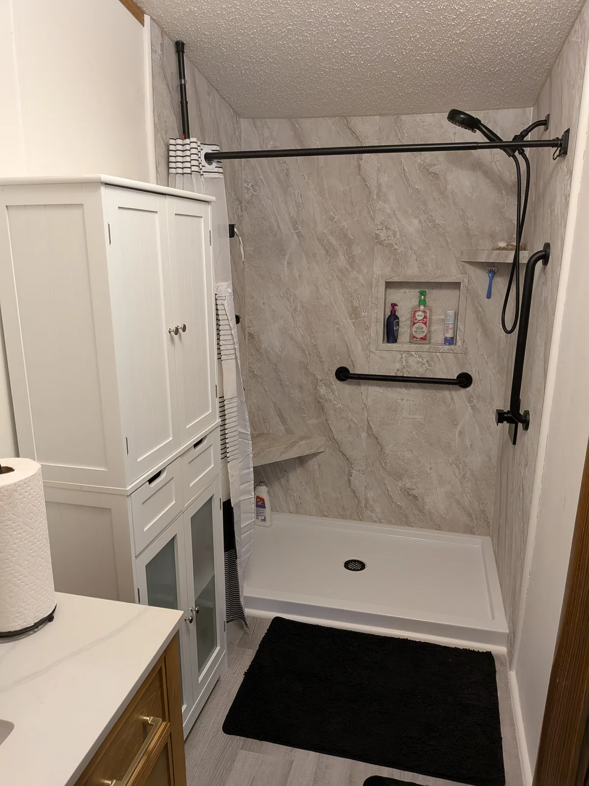 Shower alcove after the remodel, low-threshold base and marble-look walls