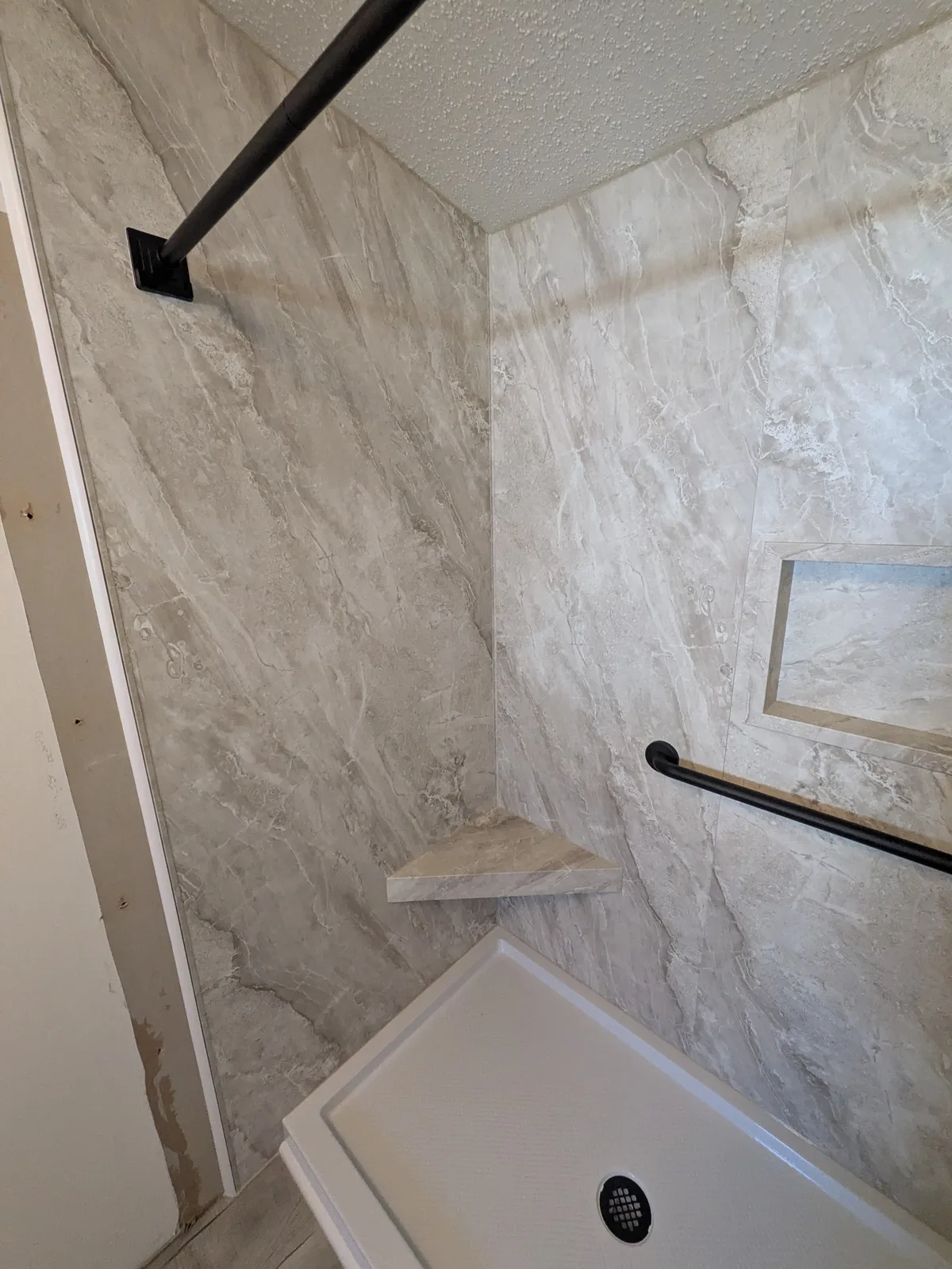 Finished shower with black fixtures and a fold-down seat