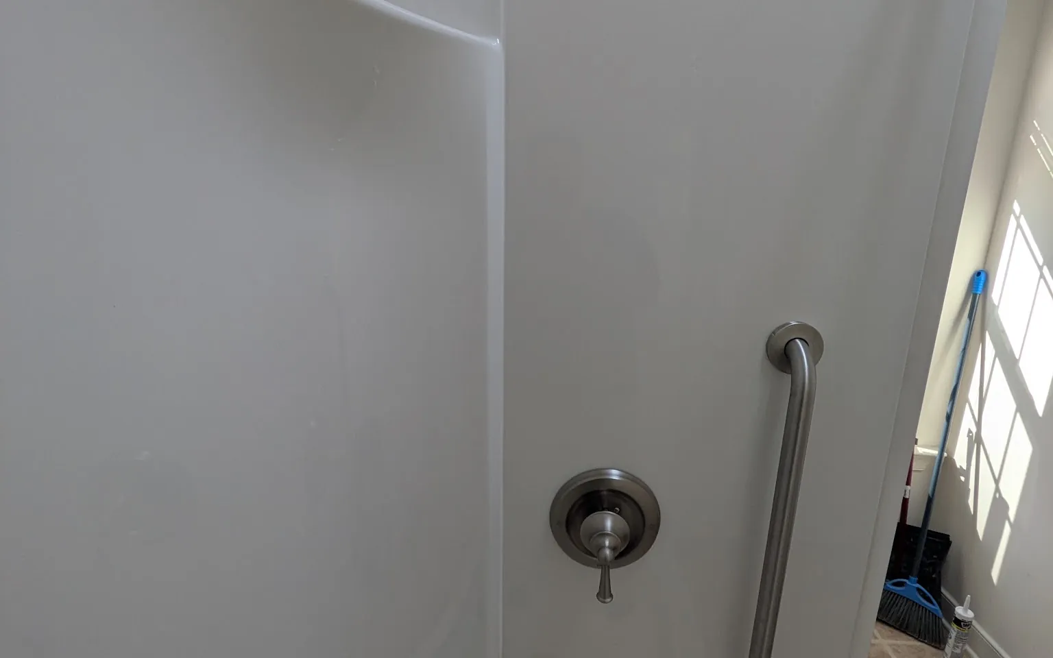 Walk-in shower fitted with a grab bar, bench and sliding glass door