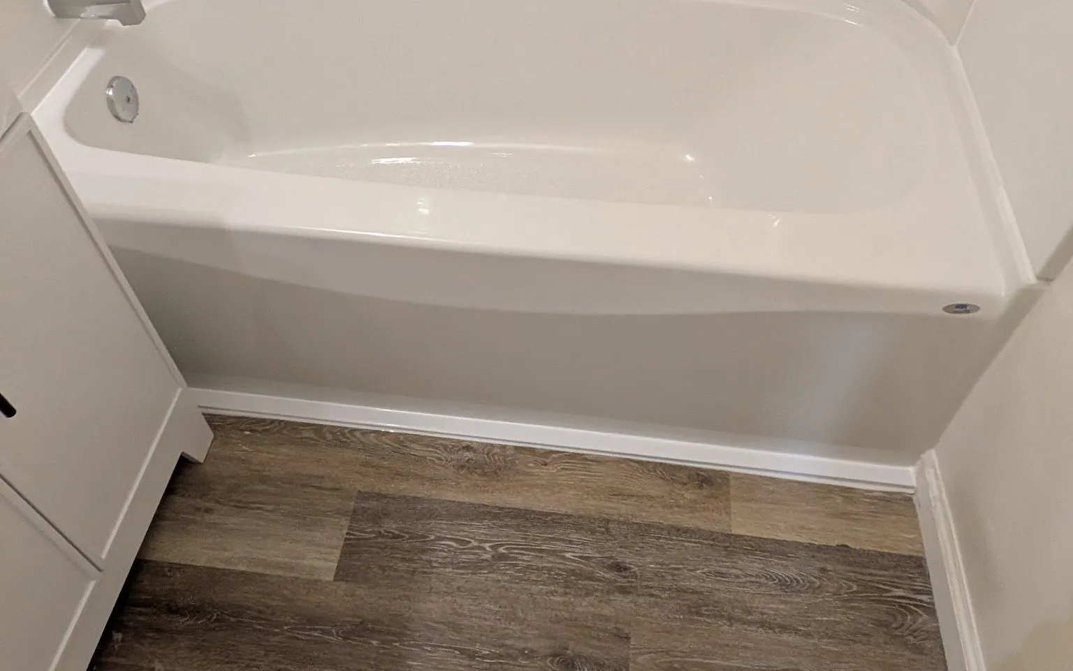 Bathroom fitted with a new tub, tiled surround and wood-look plank flooring