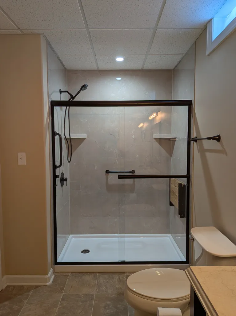The finished shower from the doorway, bronze framed doors set against the tiled alcove