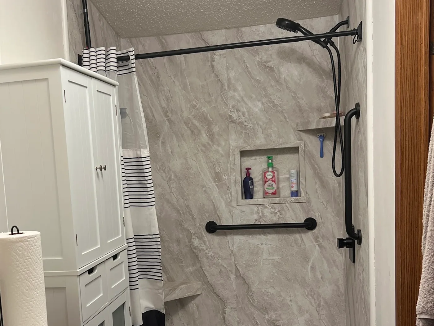 Remodeled family bathroom with a low-threshold walk-in shower, stone-look walls and a quartz vanity top
