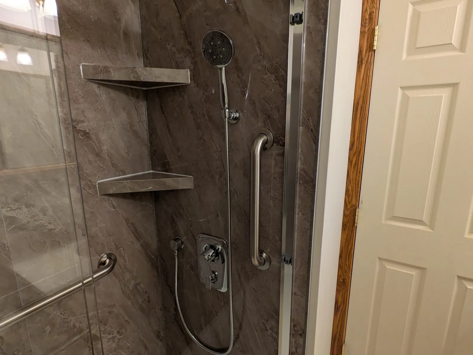 Shower fitted with a new handheld shower system, grab bar and sliding glass door